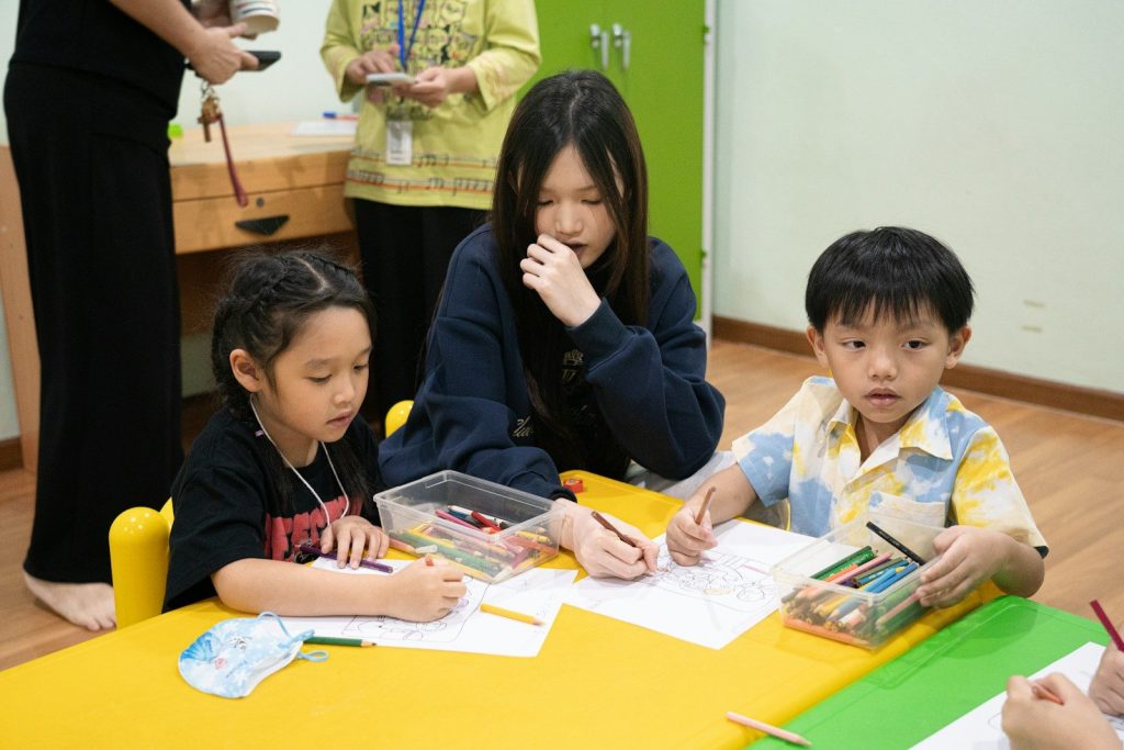 Children drawing with a teacher at a table