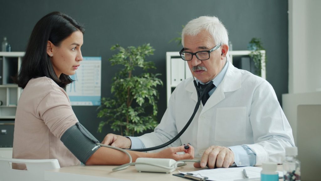 Doctor checks patient's blood pressure with stethoscope