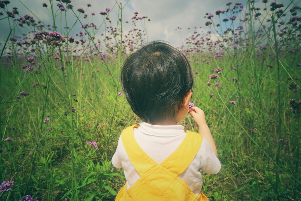 girl in yellow shirt standing on green grass field