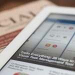 white tablet computer on top of newspaper