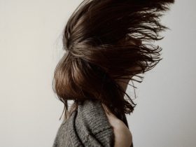 woman in gray sweater standing near white wall