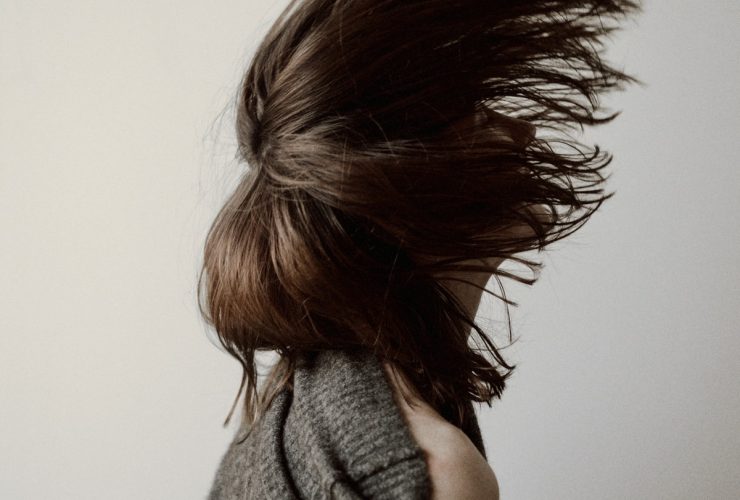 woman in gray sweater standing near white wall
