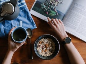 person holding blue ceramic mug and white magazine