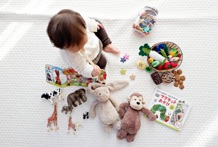 boy sitting on white cloth surrounded by toys