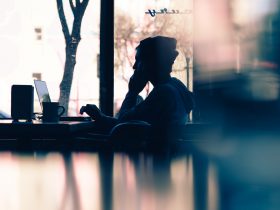 silhouette of a person sitting in front of a laptop