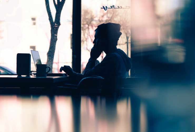 silhouette of a person sitting in front of a laptop