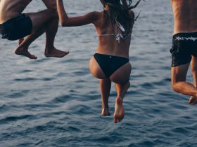 one woman and two men jumping at sea