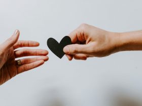 person reaching black heart cutout paper