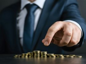 A man in a suit pointing at a pile of gold coins