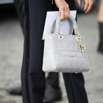 person in black pants holding white leather handbag