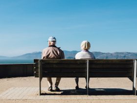 man and woman sitting on bench facing sea