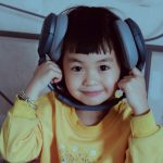a young boy wearing headphones while sitting on a bed