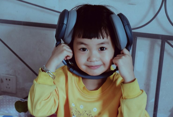 a young boy wearing headphones while sitting on a bed