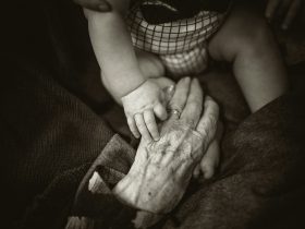 an older woman holding a baby's hand