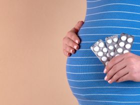 pregnant woman in blue dress holding blister pack