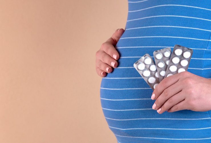 pregnant woman in blue dress holding blister pack