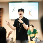 A man gestures enthusiastically while presenting to an audience