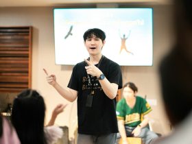 A man gestures enthusiastically while presenting to an audience