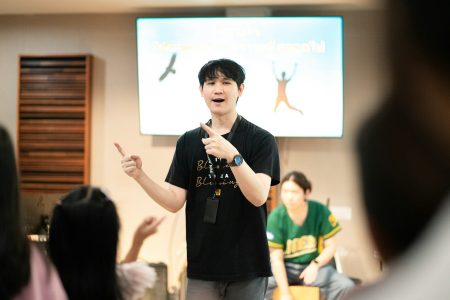 A man gestures enthusiastically while presenting to an audience