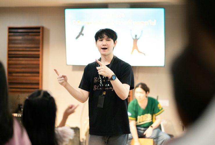 A man gestures enthusiastically while presenting to an audience